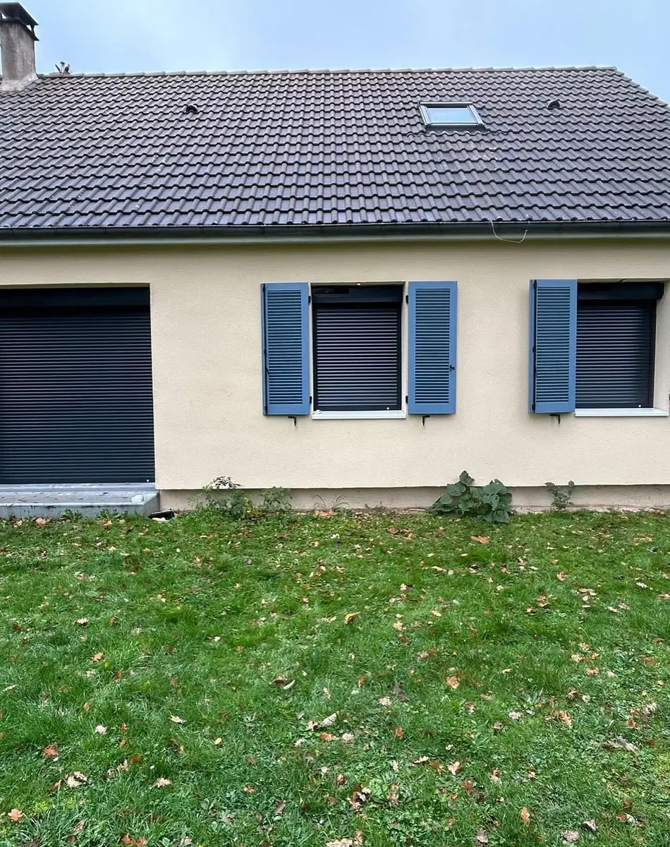 Maison avec volets bleus et pelouse verte