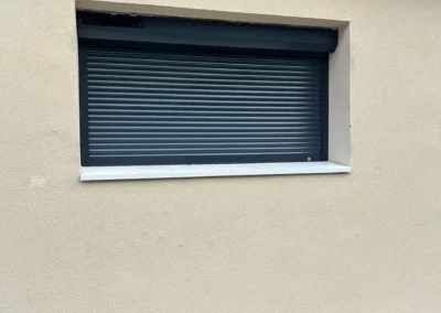 Fenêtre avec volet roulant fermé sur mur beige