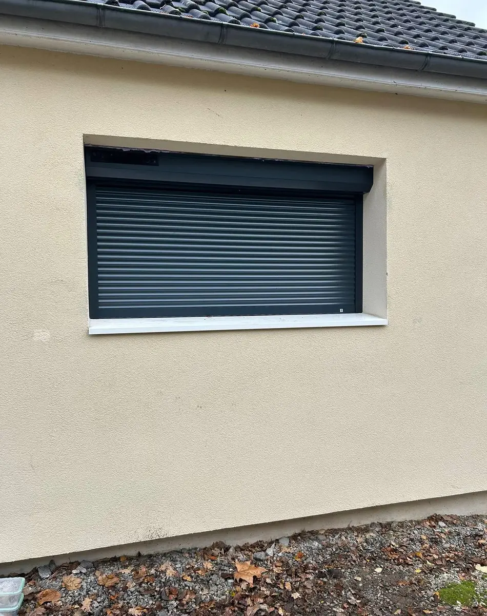 Fenêtre avec volet roulant fermé sur mur beige