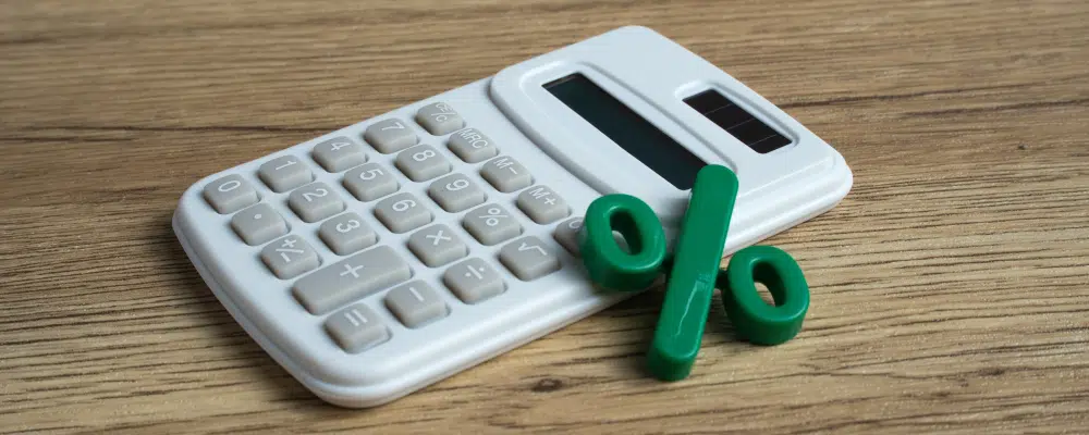 Calculatrice blanche avec symbole de pourcentage vert sur bois