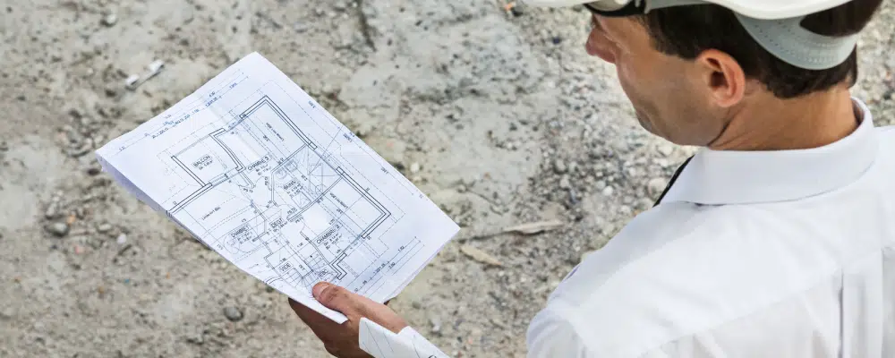 Homme en casque examinant un plan de construction